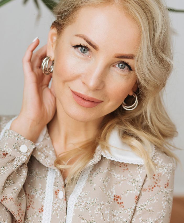 Smiling woman with blonde hair and floral blouse.
