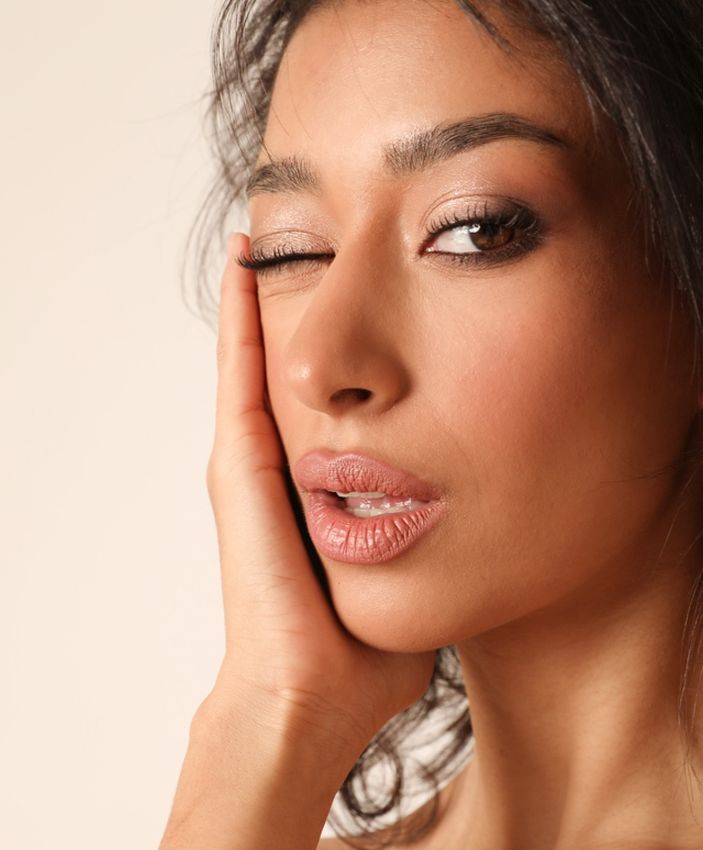 Woman winking with hand on her face.