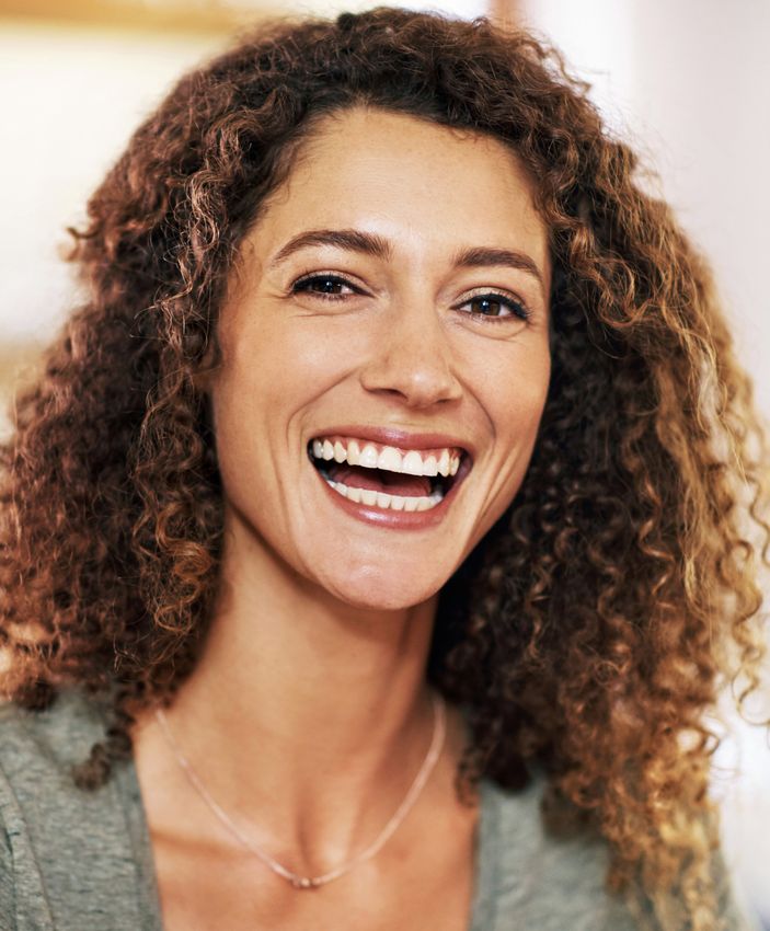 Smiling woman with curly hair indoors.
