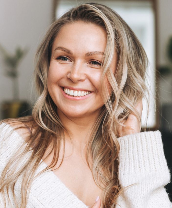 Smiling woman with long hair in cozy sweater.