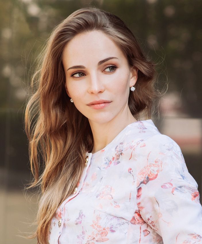 Smiling older woman with elegant hairstyle and jewelry.